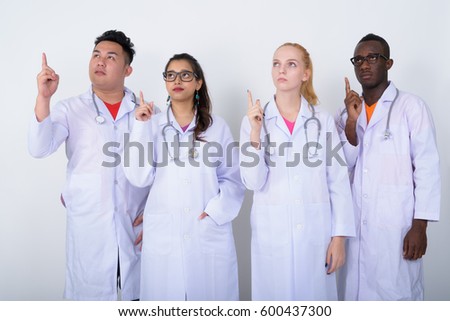 Studio shot of diverse group of multi ethnic doctors thinking while pointing finger up together