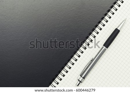 Pen with notebook on blackboard background