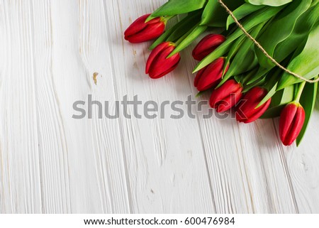 Bouquet red  tulip flowers with easter eggs on old wooden table