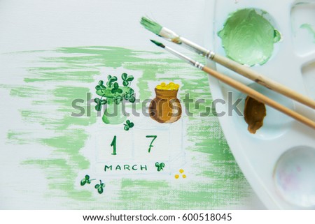the process of drawing and preparing for the holiday Background, greeting card for St. Patrick's day: pot of coins, green hat, clover, March 17, brushes, palette, paint
