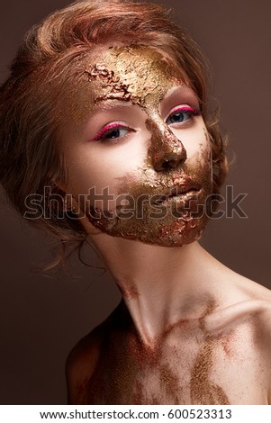 Young girl with creative makeup and textures on her face. Beautiful model with raspberry arrows and golden pigment. Photo is taken in the studio. Beauty of the face