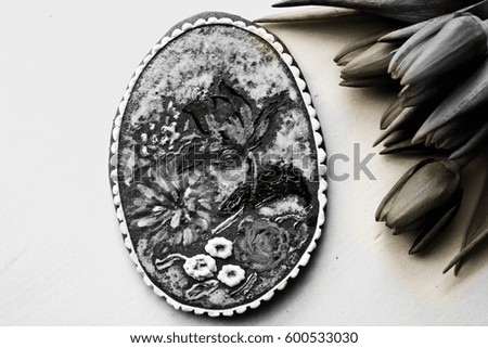 gingerbread decorated as painted egg, oval shape. floral ornaments, tulips on the side, black and white
