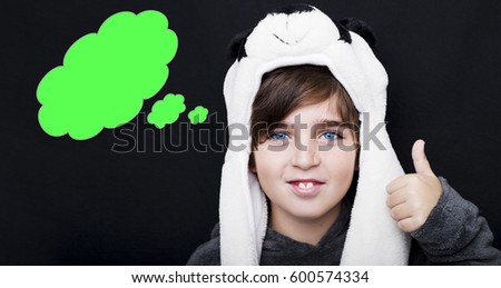 Handsome boy in panda hat giving thumbs up sign with an empty thought bubble on black background. 