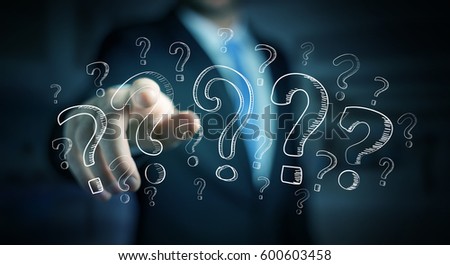 Businessman on blurred background touching hand drawn question marks with his fingers Royalty-Free Stock Photo #600603458