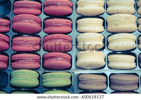 Background - tasty colorful macarons, macaroons, traditional French cookies on in plastic box, top view