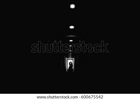 Row of lamps shine in a dark corridor where newlyweds kiss