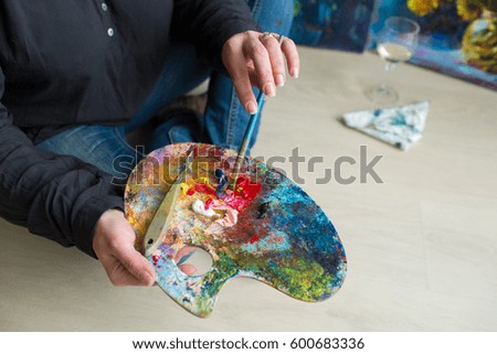painter holding artistic palette with paint, a brush and a palette knife