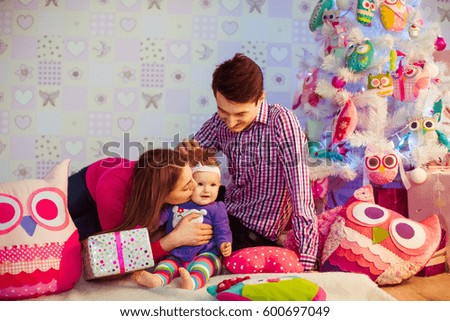 Man in plaid shirt plays with little girl before toy Christmas tree