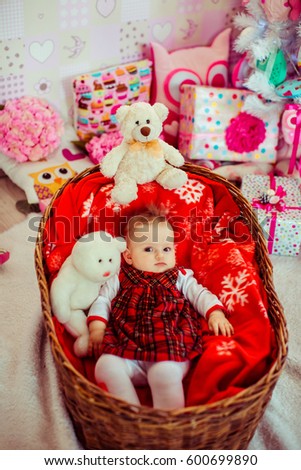 Little girl in red plaid dress lies in large basket