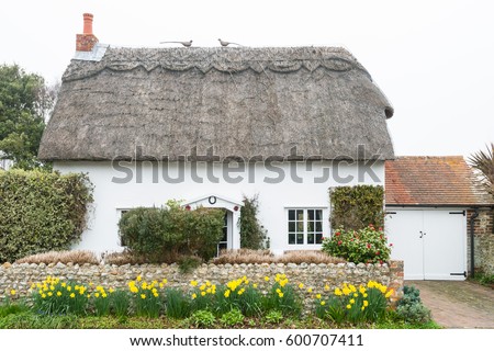 Traditional Old English Cottage with Thatched Roof Royalty-Free Stock Photo #600707411