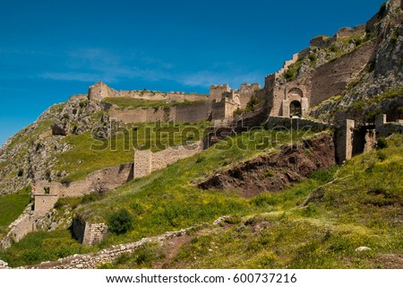 The ruins of medieval fortress of Acrocorinth up on the hill, the inner part is surrounded by old walls, on a bright sunny day, Peloponnese, Greece Royalty-Free Stock Photo #600737216