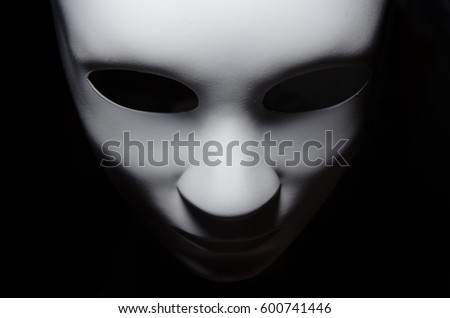 White mask with neutral expression and shadows on dark background.