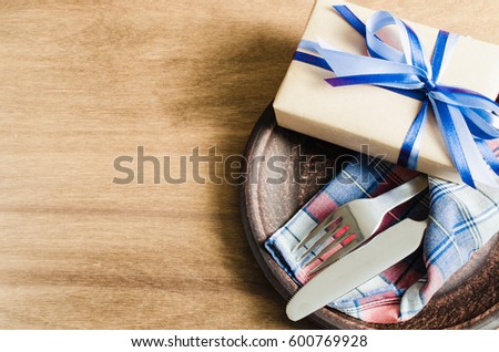 Festive Table Setting. Cutlery with Present on Linen Napkin on Rustic Wooden Background. Father's Day Concept. Copy Space. Selective Focus. Royalty-Free Stock Photo #600769928