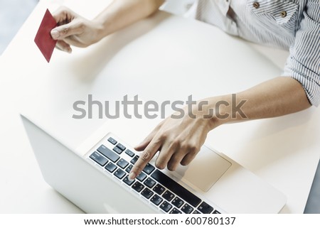 Woman using laptop and mobile phone to online shopping and pay by credit card. This picture is focus at woman's hand and use warm bright sunlight filter for feeling comfortable
