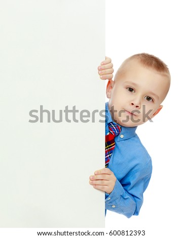 Beautiful little boy in a blue shirt and tie peeking from behind the banner.Isolated on white background.