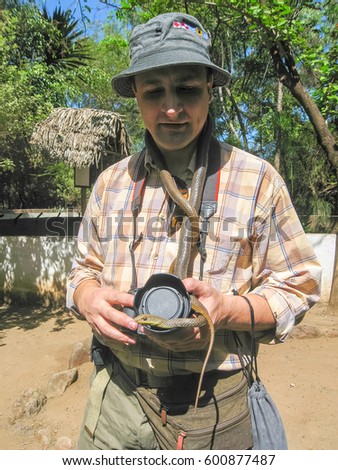 Photographer stands with snake tied like cravat on his neck. Arusha, Tanzania, Africa.

