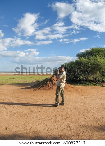 Photographer stands and takes a picture of landscape. Lake Manyara National Park, Tanzania, Africa.
