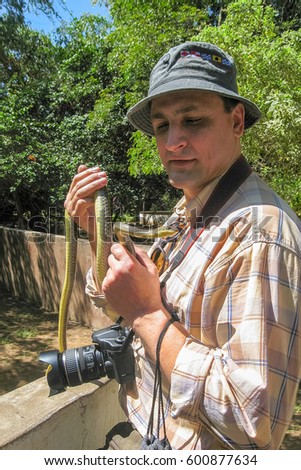 Photographer stands with snake tied like cravat on his neck. Arusha, Tanzania, Africa.
