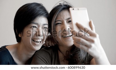 Two mixed race Asian girls taking selfie with smart phone