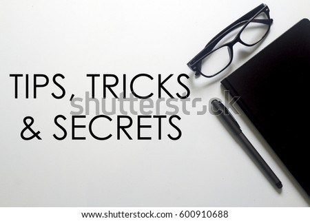 A business concept. A glasses, pen and notebook with TIPS, TRICKS AND SECRETS written on white background.