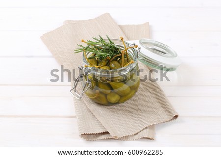 jar of pickled caper berries on beige place mat