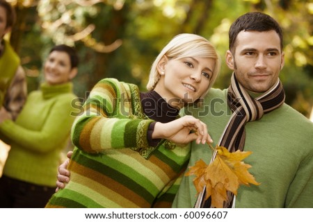 Closeup portrait of young couple embracing in autumn park, woman holding leaves.?