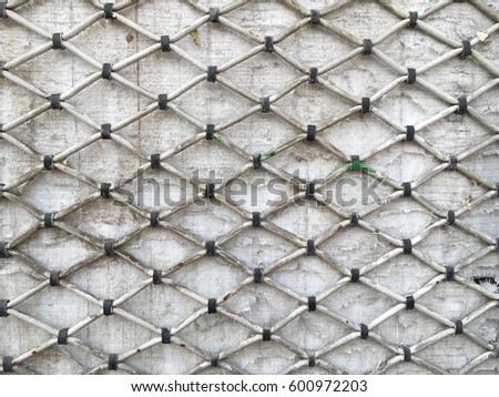 The metal net on the white colored wooden wall.