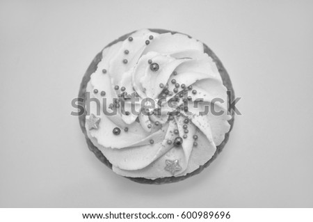 Cupcake with cream and gold confectionery sprinkling, view from above. Black and white. Picture for a menu or a confectionery catalog.
