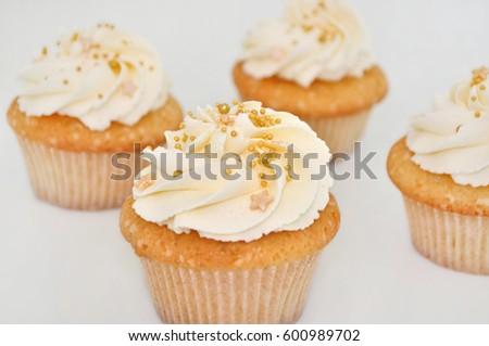 Cupcake with cream and gold confectionery sprinkling, with blurred background. Picture for a menu or a confectionery catalog.