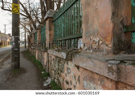 Old wooden fence on ruined stone foundation. Old door, short; Wicket, section in ruined fence of an abandoned villa, giving in poor quarter of Odessa. Decline and poverty in urban landscape. Trash