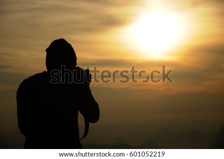 Silhouette of a photographer who shoots a sunrise in the mountains