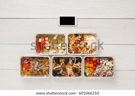 Internet order of healthy restaurant food, mockup background. Fresh diet daily meals delivery. Vegetables, seafood, meat and fruits in foil box. Top view, flat lay on wood, copy space