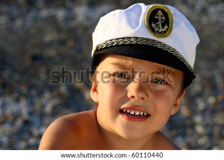 Portrait of three boys in the captain's cap, on the background (blurred) of sand and water./My Captain