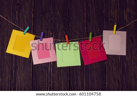 Multicolored photo frames on a wooden background with clothespins.