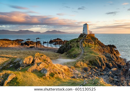 Sunset at Ynys Llanddwyn island on the coast of Anglesey in North Wales with the mountains of Snowdonia in the distance. Royalty-Free Stock Photo #601130525