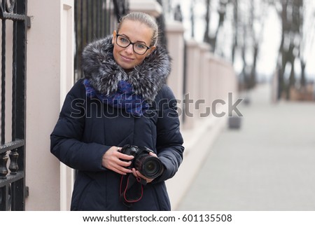 Beautiful girl with a camera walks in the park.