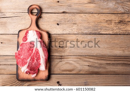 Raw meat on wooden background. Raw beef steak on cutting board. Cooking meat. Top view