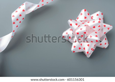 White bow and ribbon with hearts on a gray background