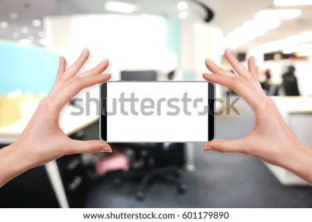 female holding a smartphone isolated blank screen with two hands on abstract blur background of modern office with nobody, ready for snap a picture