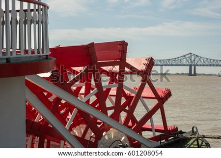 Looking at a red paddlewheel and back at the farthest downstream bridge on the Mississippi River.  Copy space in upper part of frame. Royalty-Free Stock Photo #601208054
