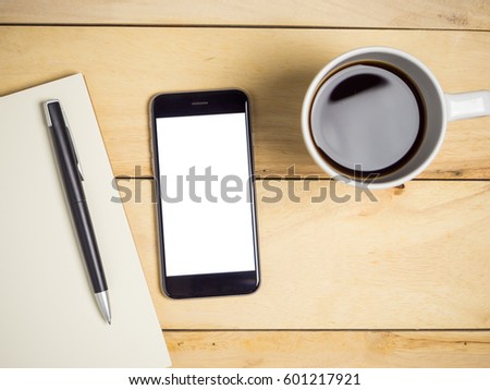Blank screen smart phone with coffee and pen on wooden table.