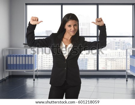 corporate portrait of young attractive latin woman wearing formal suit smiling happy and confident at modern office next to window in business success concept