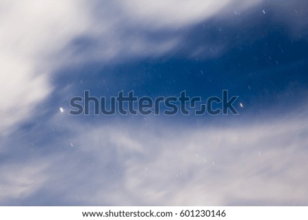 Beautiful night landscape with clouds and traces of the stars in the night sky against a background of mountains, shot with a long exposure
