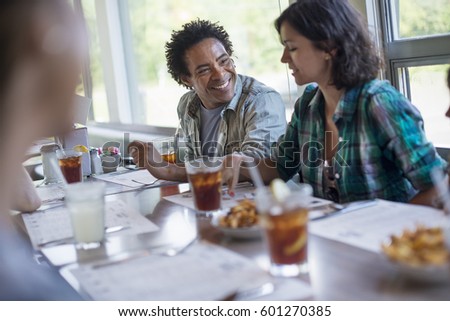 A group of friends eating at a diner A couple seated side by side