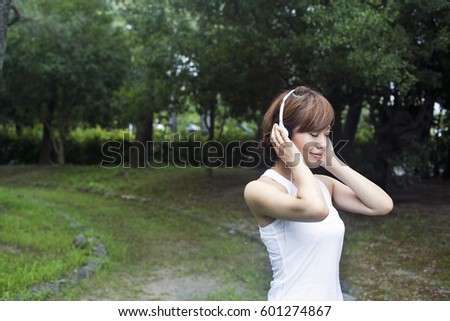 A woman in a Kyoto park, wearing headphones Wearing jogging kit