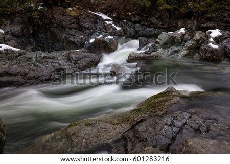 Nature view on the snow covered valley with the river flowing in between the rocks. Picture taken near Tofino, Vancouver Island, British Columbia, Canada.