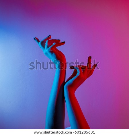 Woman hands on isolated background in red and blue light, square image.