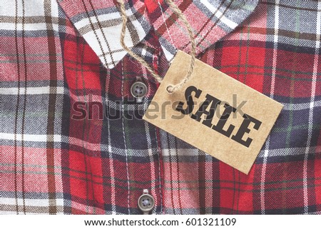 Sale tag made of recycled paper on clothes background
