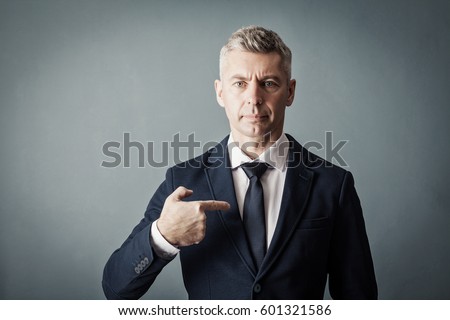 Businessman is pointing at himself on gray background Royalty-Free Stock Photo #601321586