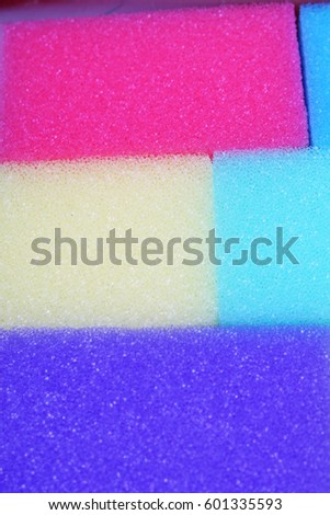 Cleaning kitchen sponge texture as background. Colorful yellow pink green purple blue multicolor sponges. Close up macro about sponges. Sponge pattern textures concept background or wallpaper 
